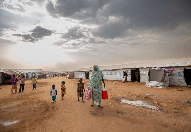 Fairuz stands outside the camp with her grandchildren.