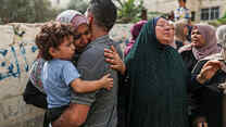 Palestinians are pictured hugging and mourning together.